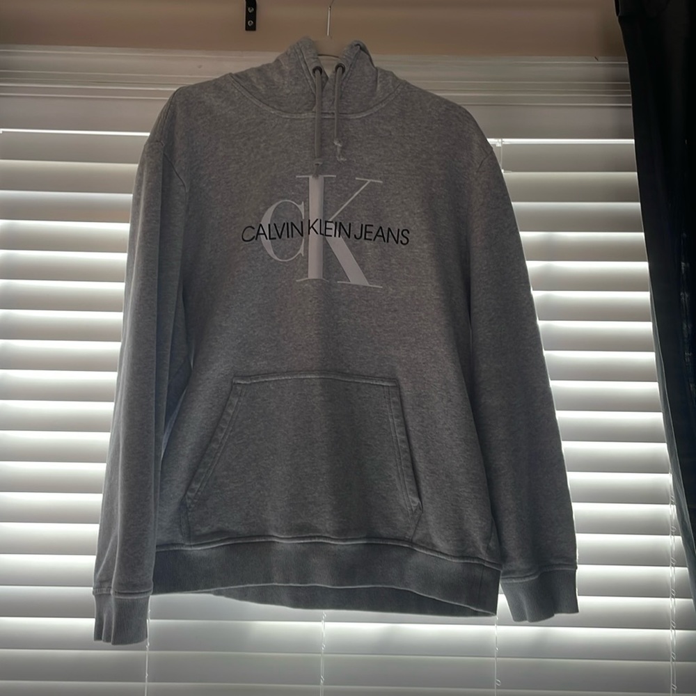 This is a XL sized sweatshirt. The color is grey. The Brand is Calvin Klein.